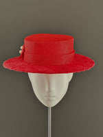 Load image into Gallery viewer, A bright red wide-brimmed hat with a matching ribbon band and small decorative pearl accents, displayed on a white mannequin head against a dark gray background.
